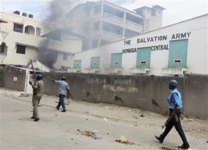 Armed policemen walk past Salvation Army Church compound set on fire by youths after protest against killing of Islamic cleric in Mombasa