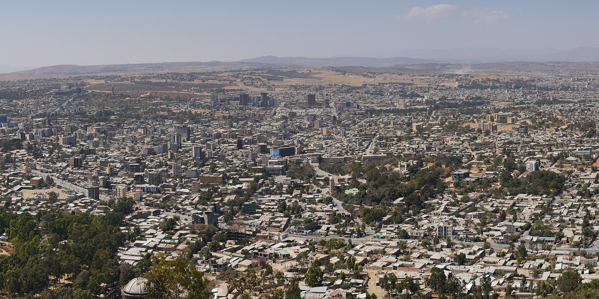 Panoramic view of Mekelle spread across hills under a clear sky, with buildings and roads in the middle distance.